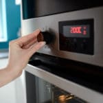 Close up of woman’s hand setting temperature control on oven
